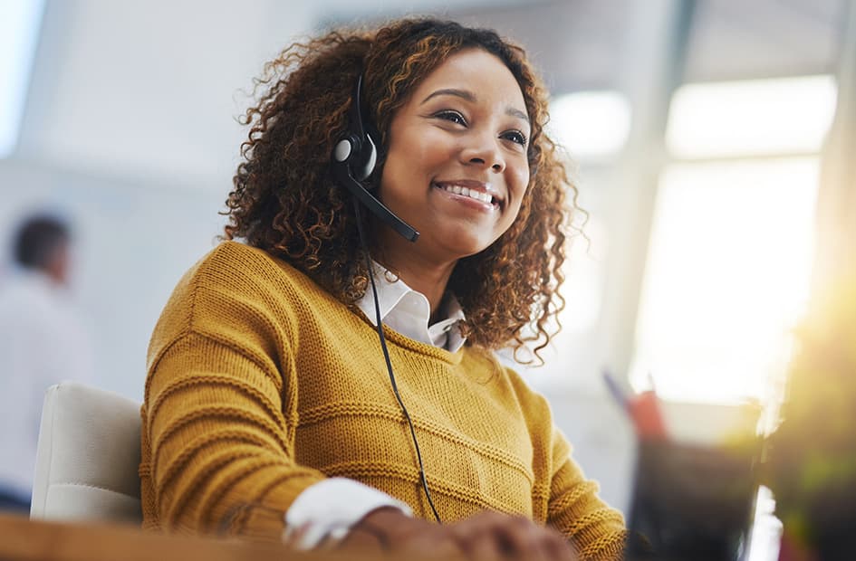 un représentant du service clientèle souriant alors qu'il est au téléphone avec un client